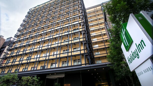 Een meerhoog gebouw met een modern architectonisch ontwerp, met een opvallend Holiday Inn bord.
