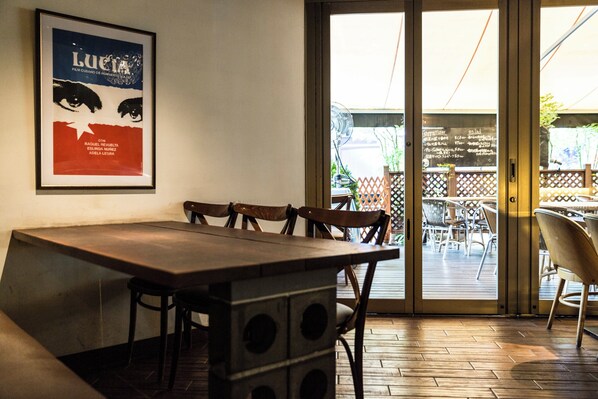 A restaurant interior with a wooden table and chairs, a poster on the wall, and a view of the outdoor seating area through a glass door. - Holiday Inn Osaka Namba by IHG (Osaka)