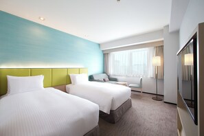Hotellihuone, jossa on kaksi sänkyä, sohva, pieni pöytä ja suuri peili.