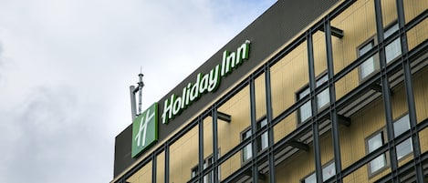 Edificio de hotel Holiday Inn con fachada moderna, ventanas amplias y un letrero llamativo.