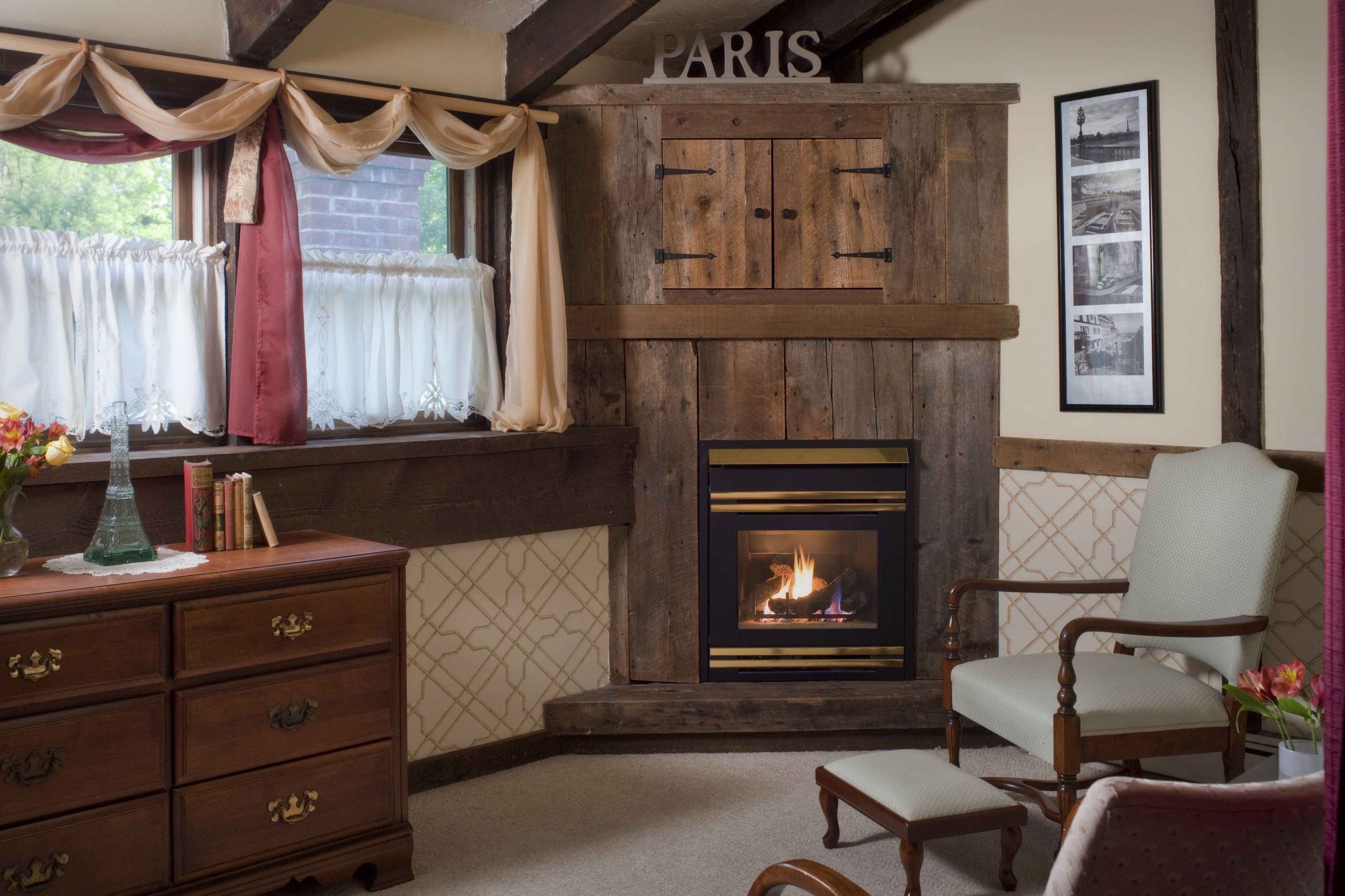Una habitación acogedora con chimenea, muebles de madera y un cartel en la pared que dice 'PARIS'.