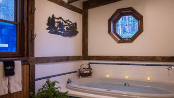 Un baño con una bañera grande, una ventana con vistas a árboles y un adorno en la pared.