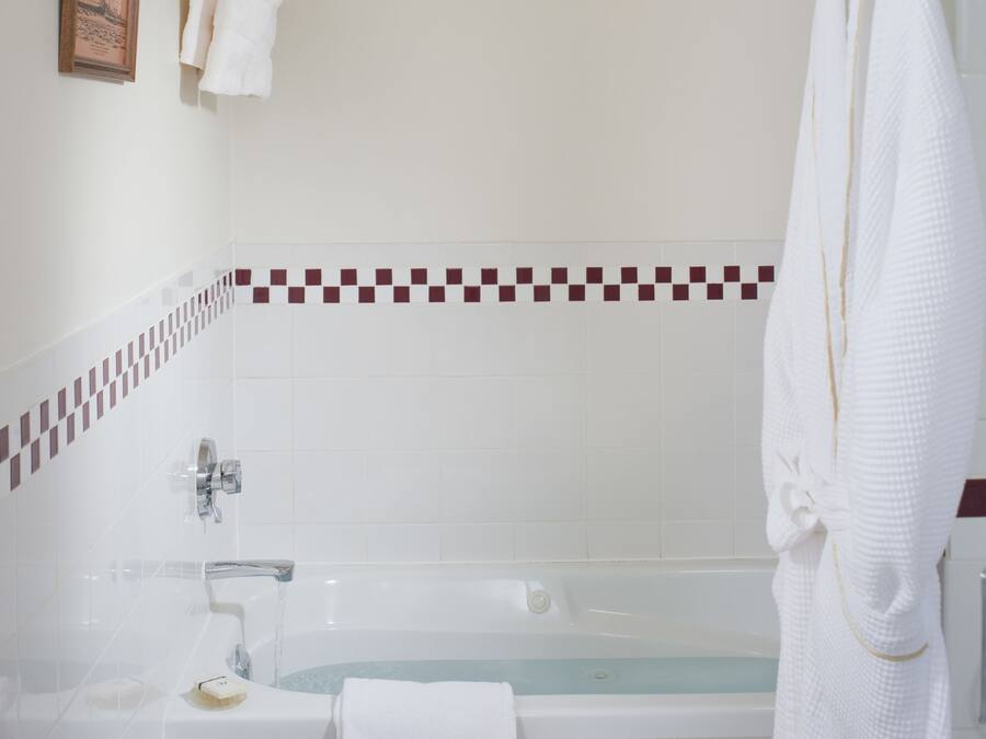 Ein Badezimmer mit Badewanne, Toilette und Handtuchhalter mit Handtüchern.