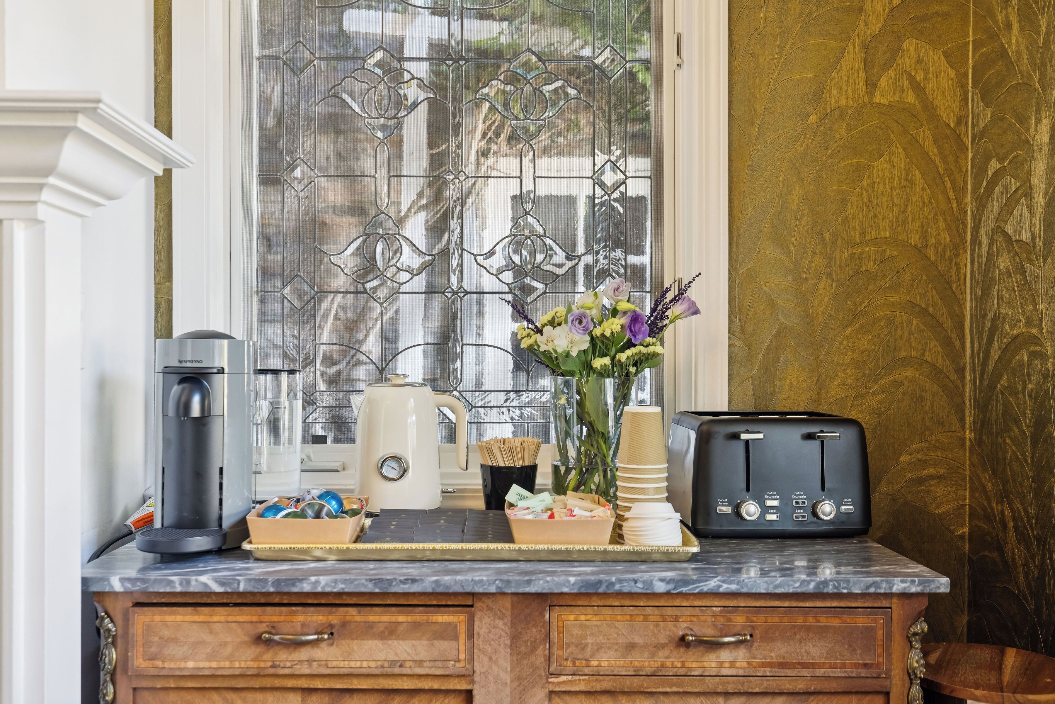A kitchen counter with a coffee maker, toaster, and a vase of flowers.