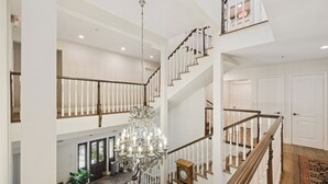 A spacious interior with a grand chandelier, a wooden staircase, and a second-floor balcony. - Mirabelle Inn (Solvang)