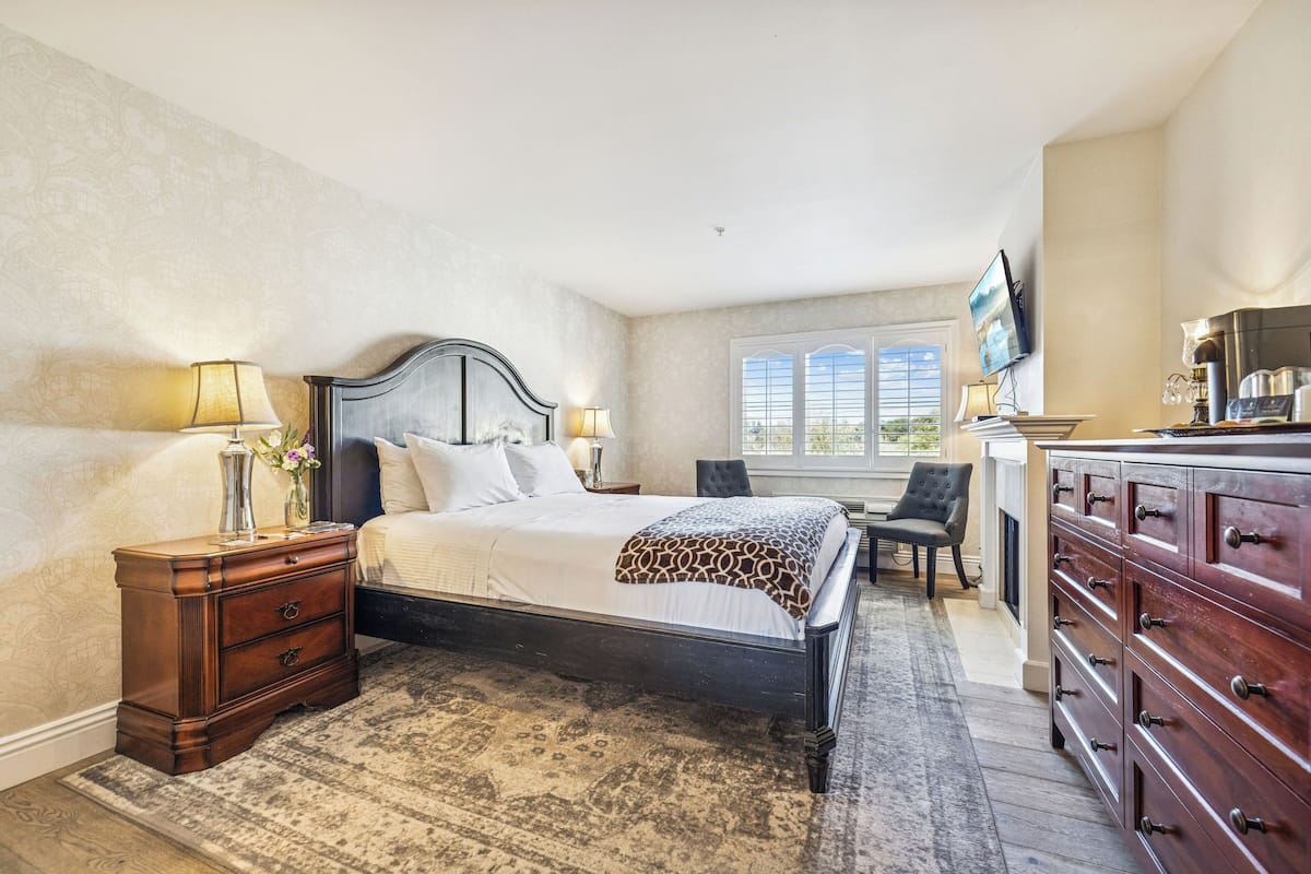 A bedroom with a bed, nightstands, a dresser, a chair, and a television.