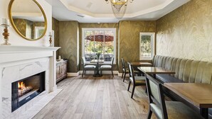 A dining area with a fireplace, a chandelier, and a view through a window. - Mirabelle Inn (Solvang)