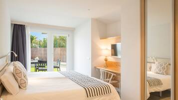 Une chambre à coucher comprenant un lit, un bureau, une chaise, un téléviseur et une porte-fenêtre coulissante donnant sur un patio.