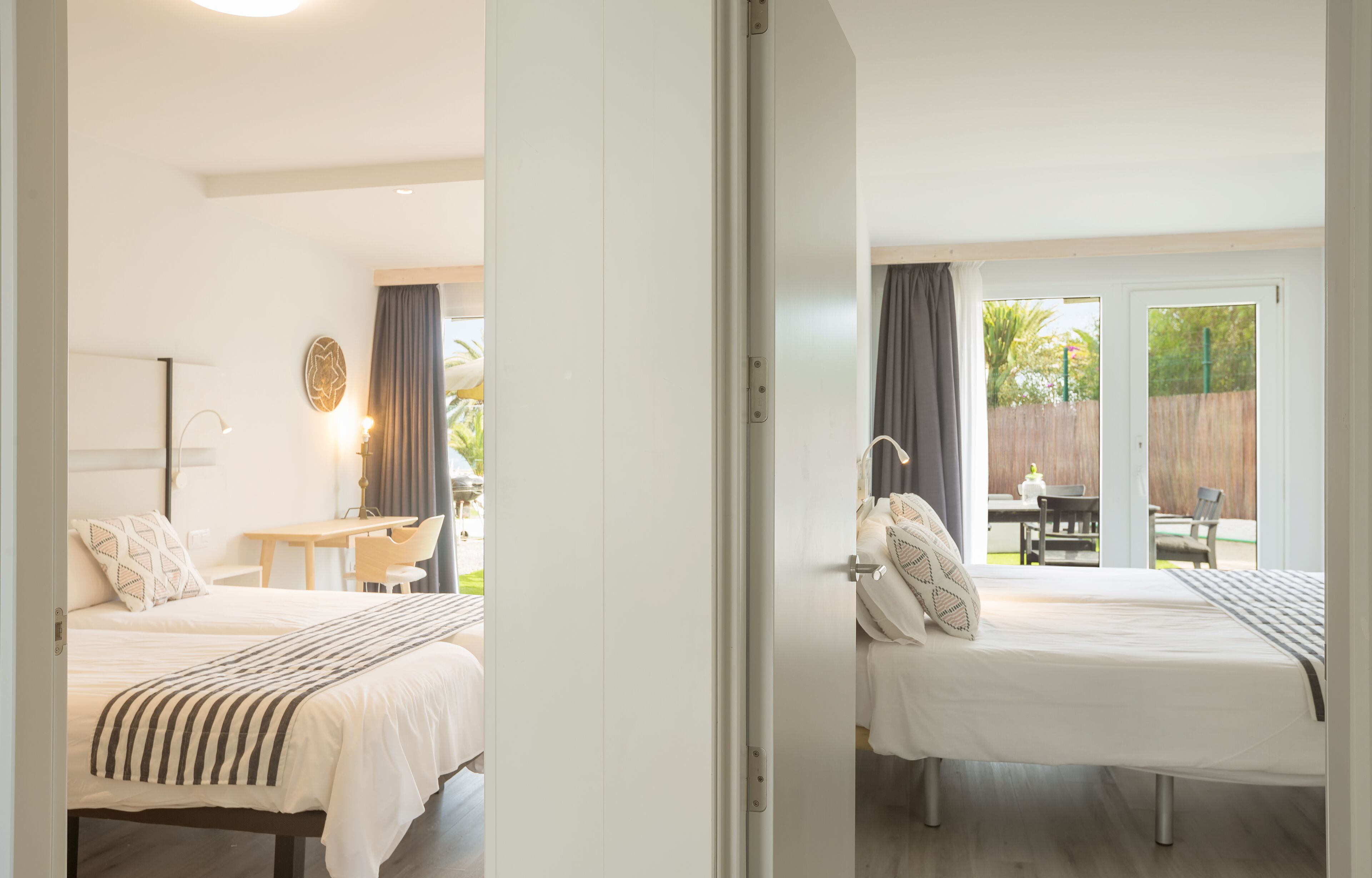 Une chambre avec un lit, une table de chevet, une lampe et une vue sur un patio extérieur.