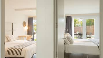 Une chambre avec un lit, une table de chevet, une lampe et une vue sur un patio extérieur.