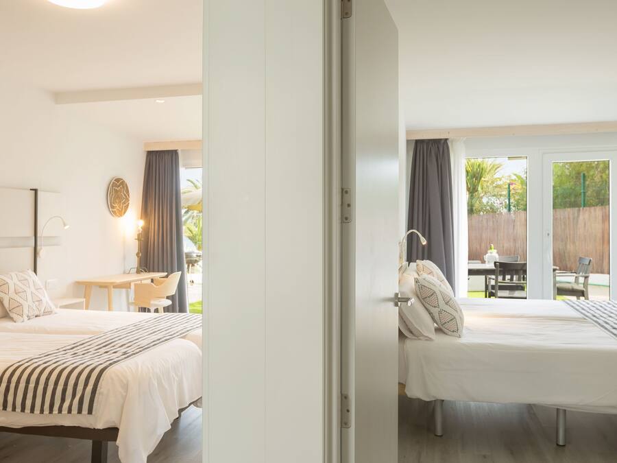 Une chambre avec un lit, une table de chevet, une lampe et une vue sur un patio extérieur.
