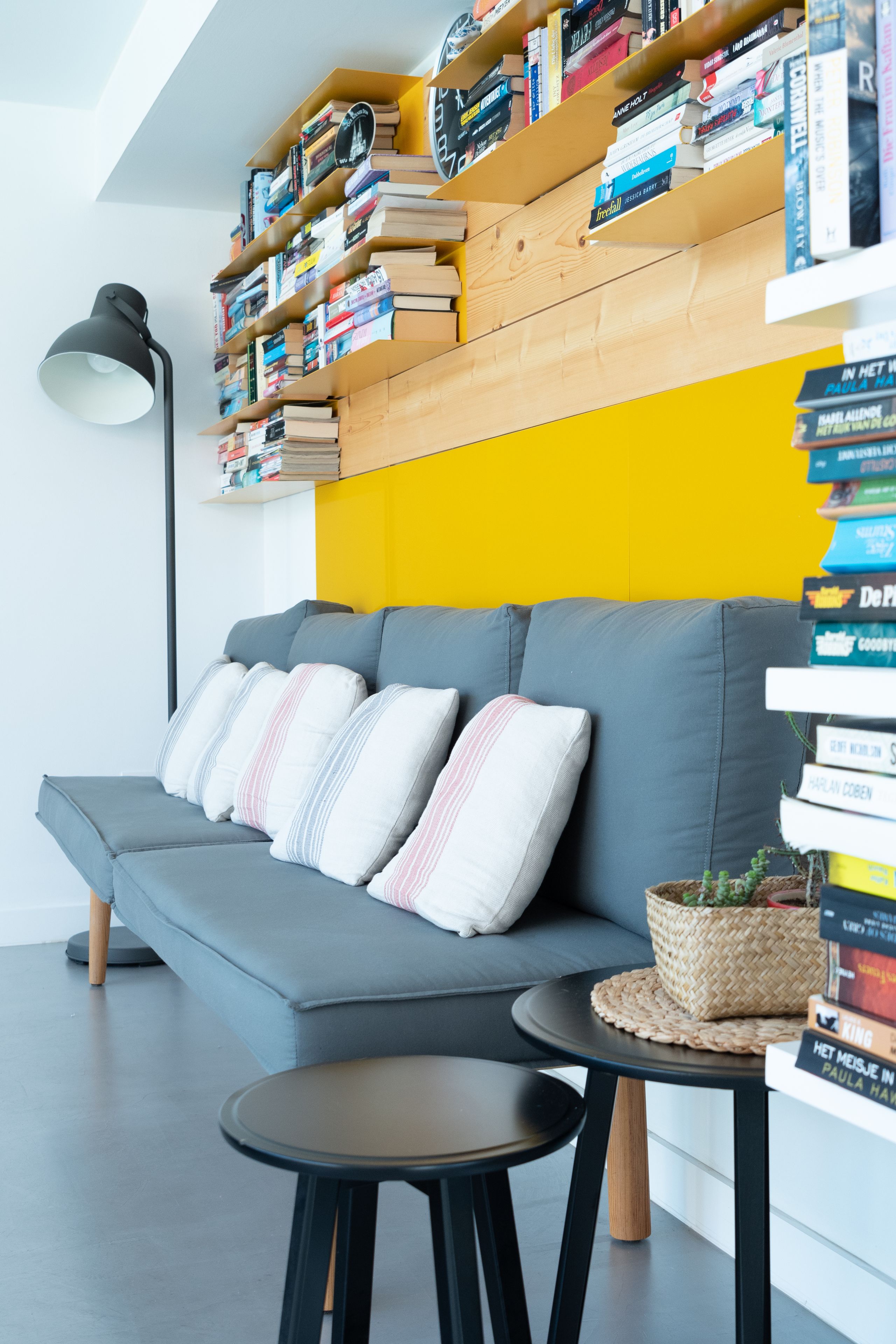 Una sala de estar moderna con un sofá gris, una mesita redonda y una estantería llena de libros.