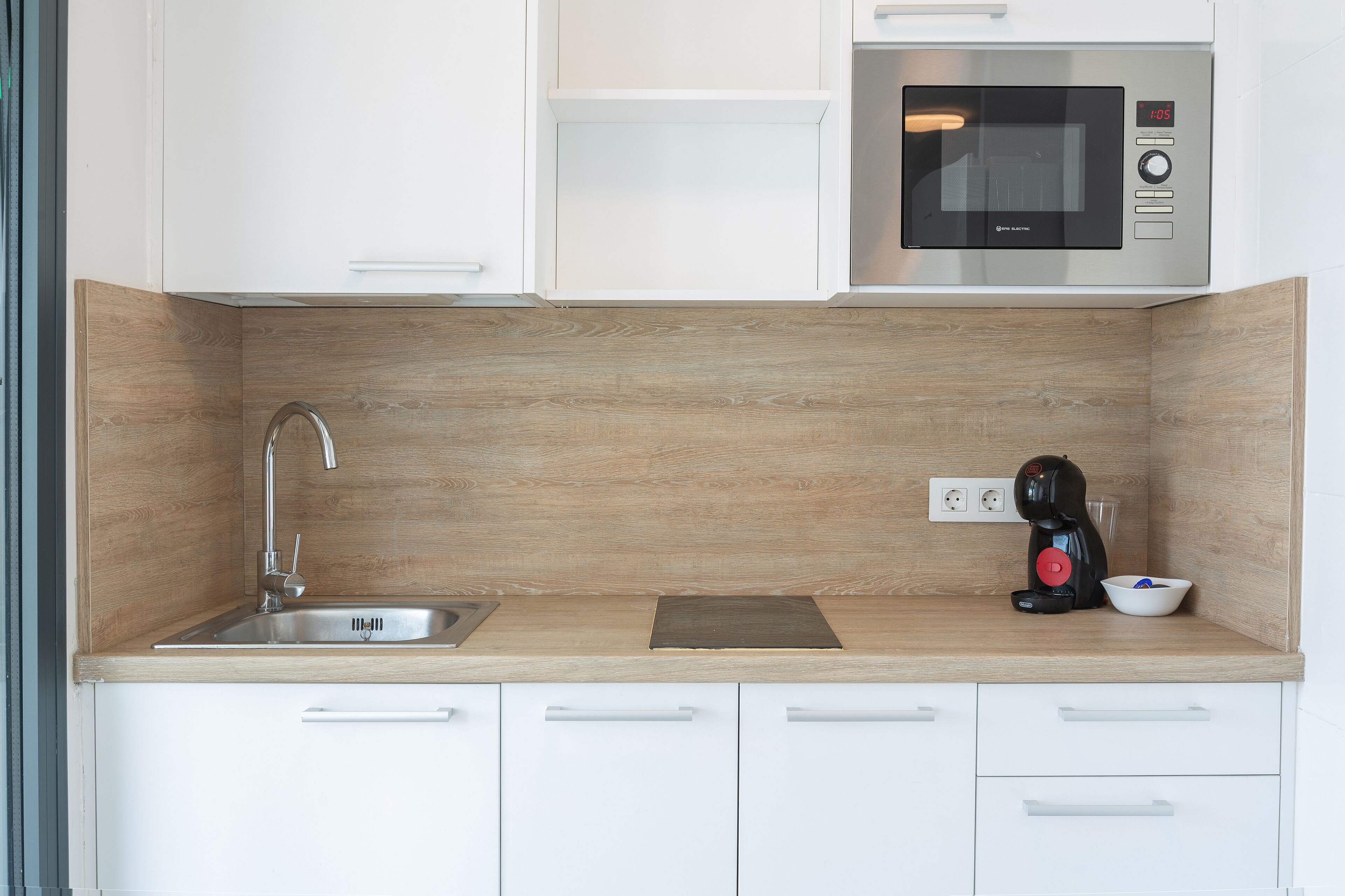 A modern kitchen with a stainless steel sink, a microwave, and a coffee maker.