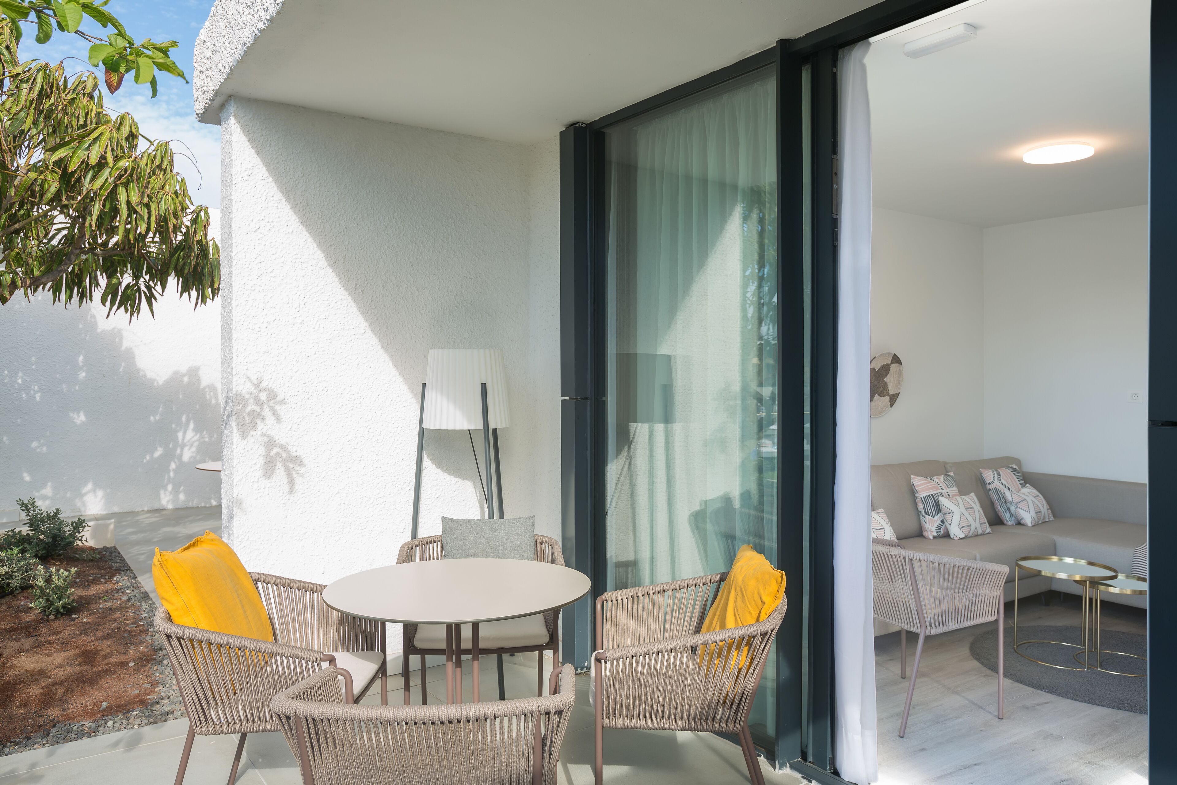 Een moderne woonkamer met een bank, een ronde tafel en rieten stoelen.