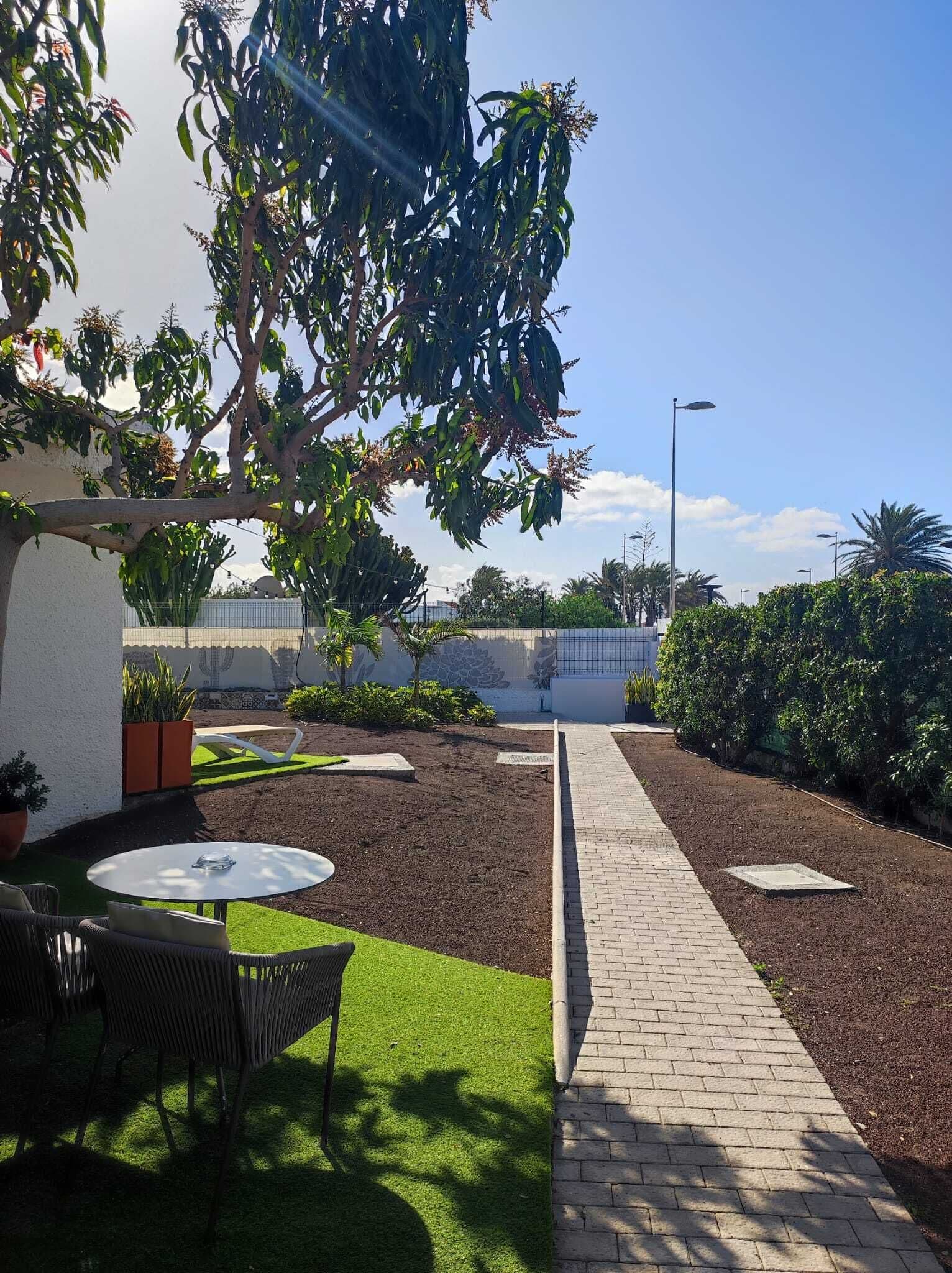 Un patio con sendero de ladrillo, césped verde y mobiliario exterior.