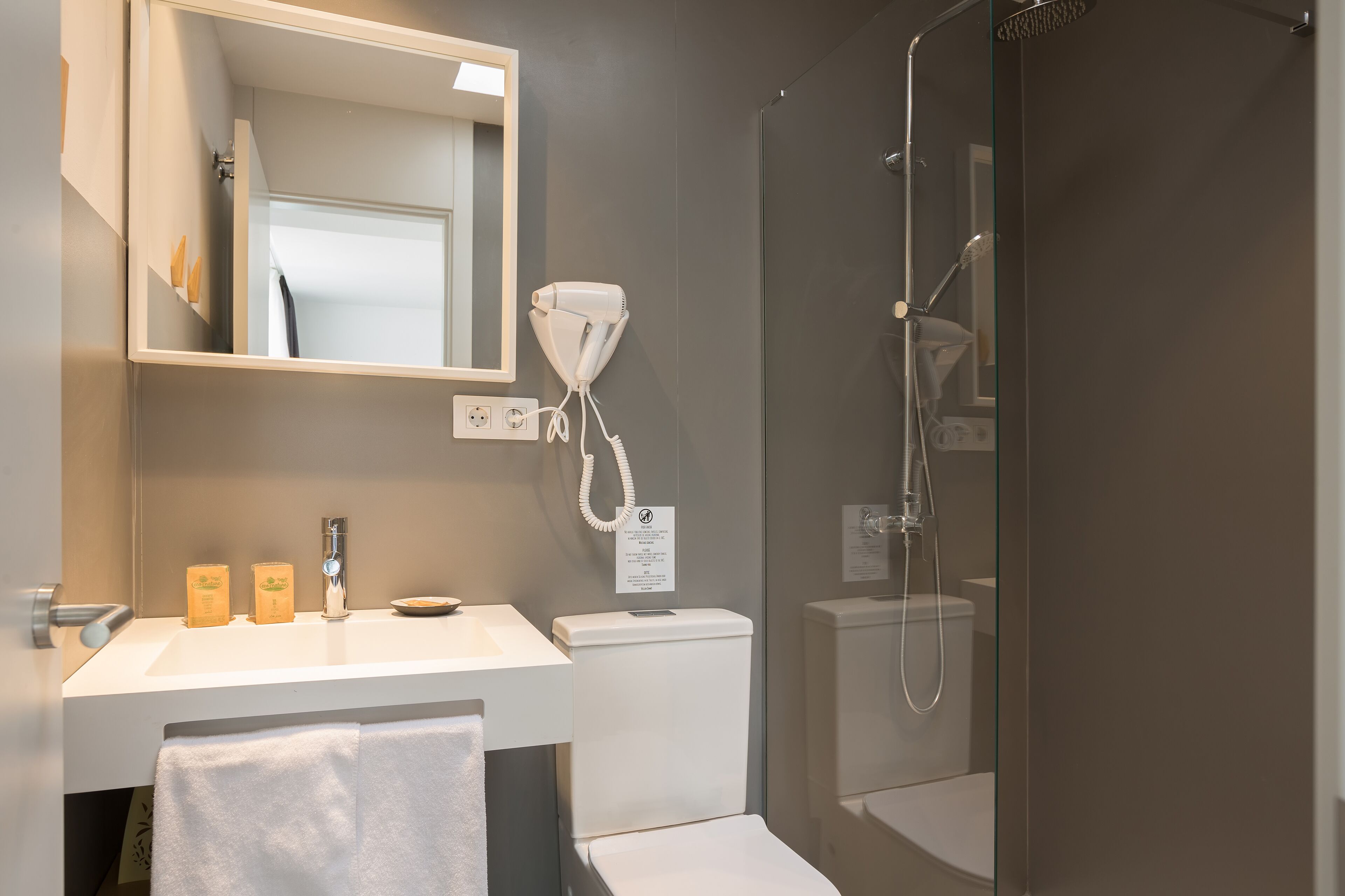 Ein modernes Badezimmer mit Waschbecken, Spiegel und Toilette in Weiß.