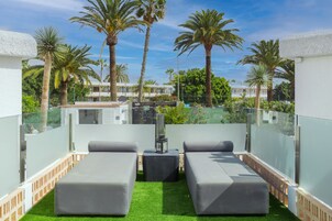 Eine Dachterrasse mit zwei grauen Lounge-Stühlen, einem kleinen Tisch und einer dekorativen Laterne.