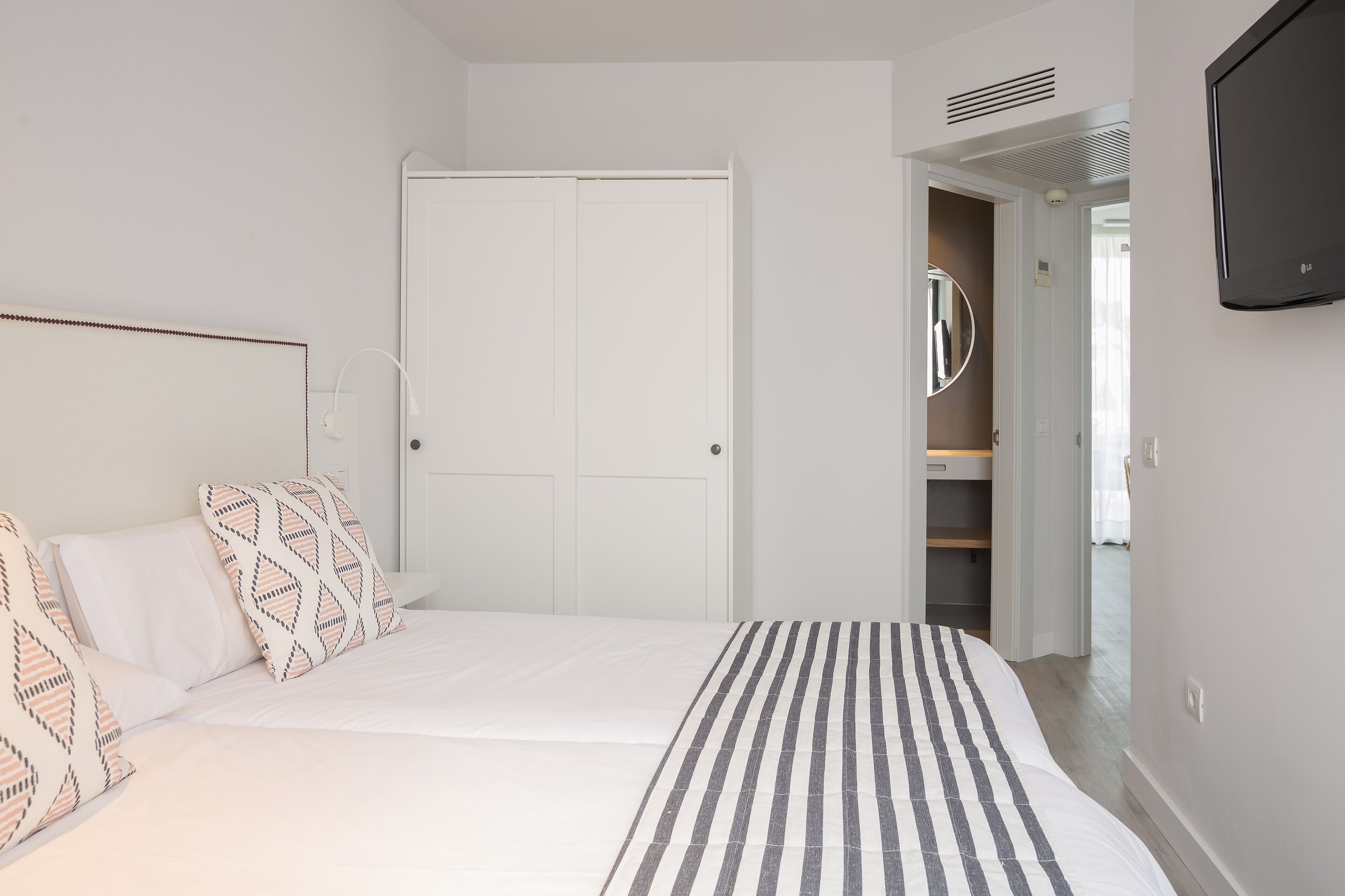 Ein Schlafzimmer mit Bett, Kleiderschrank und Fernseher.