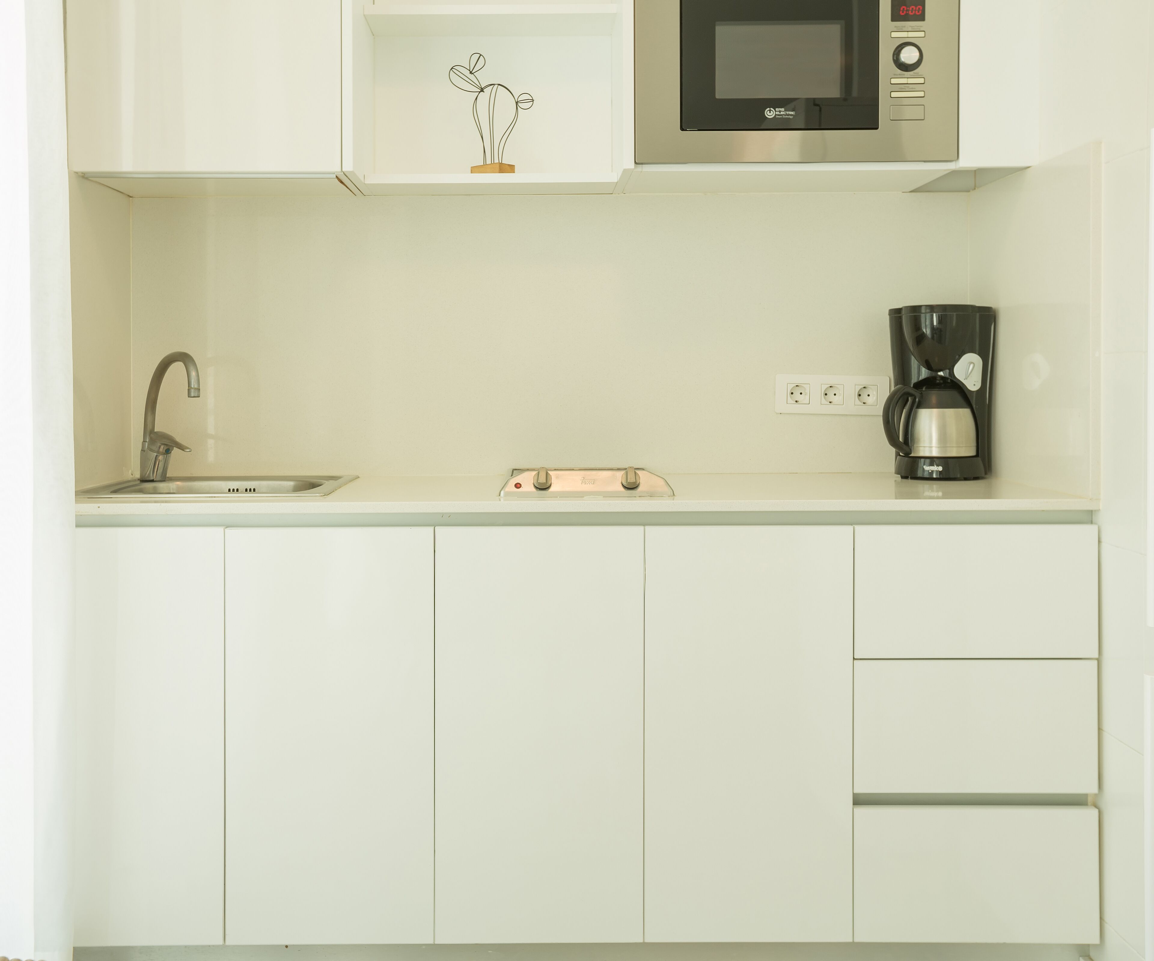 A kitchen with a microwave, coffee maker, and a sink.