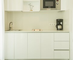 A kitchen with a microwave, coffee maker, and a sink.