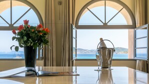 A table with a vase of red roses and a cocktail shaker, overlooking a coastal view through arched windows. - Hôtel Perla Rossa (L'Île-Rousse)