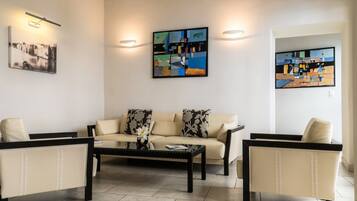 A living room with a sofa, two armchairs, a coffee table, and abstract paintings on the walls.