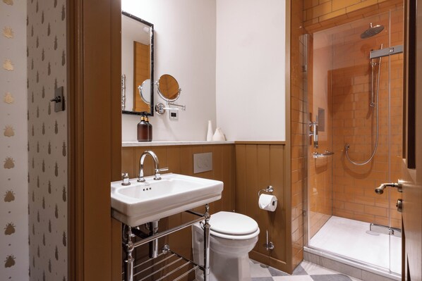 A bathroom with a sink, toilet, and a glass-enclosed shower area. - Dumbleton Hall (Evesham)