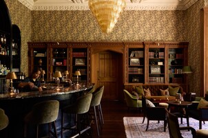 A bar area with a bartender, a wooden bookshelf, and a seating area with chairs and a sofa.