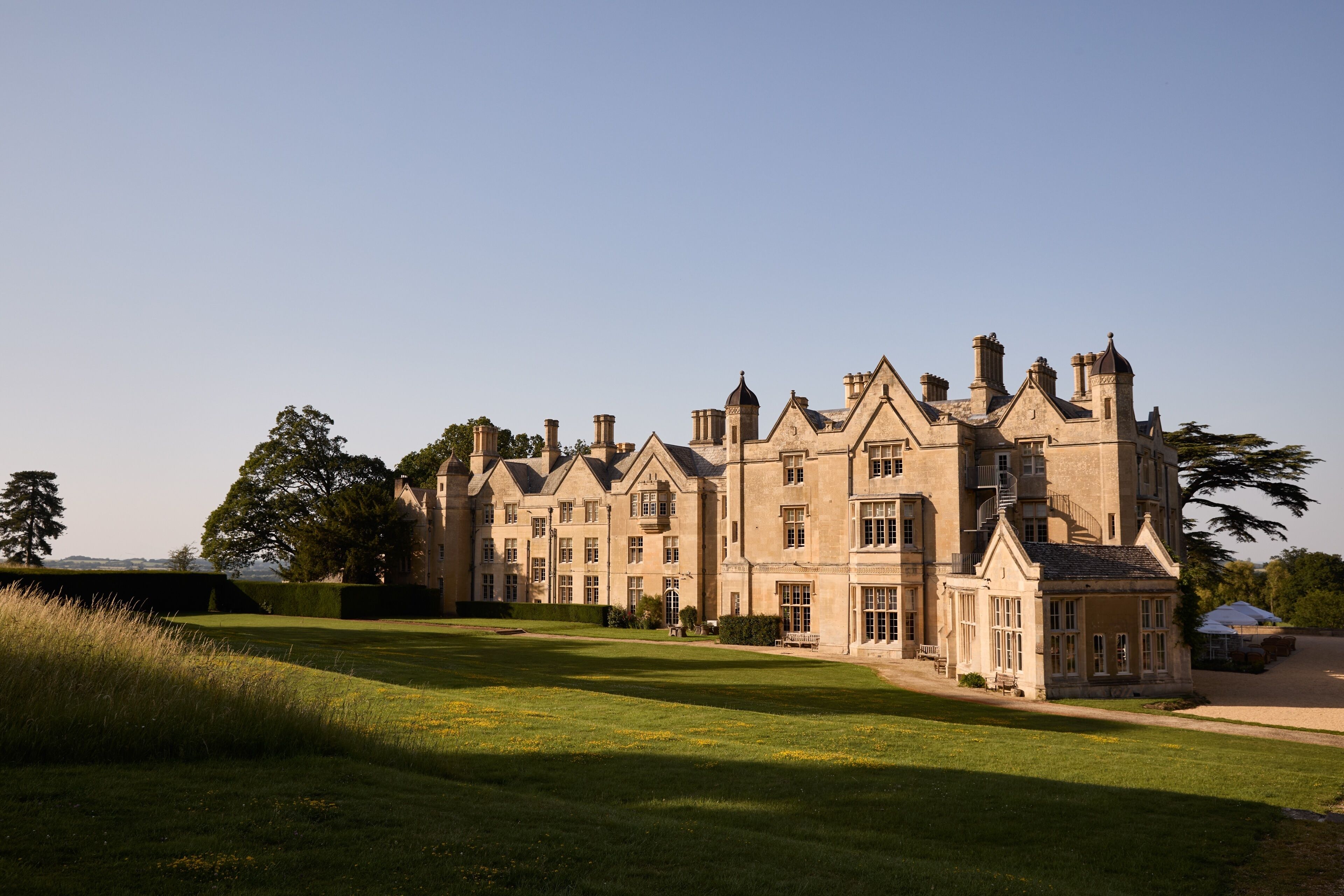 A large, historic building with multiple wings and a well-maintained lawn.