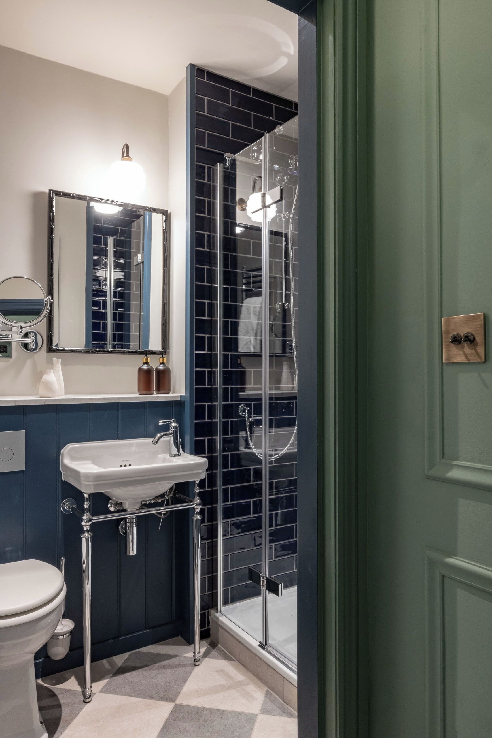 A bathroom with a white sink, a mirror, a toilet, and a shower area with a glass door.
