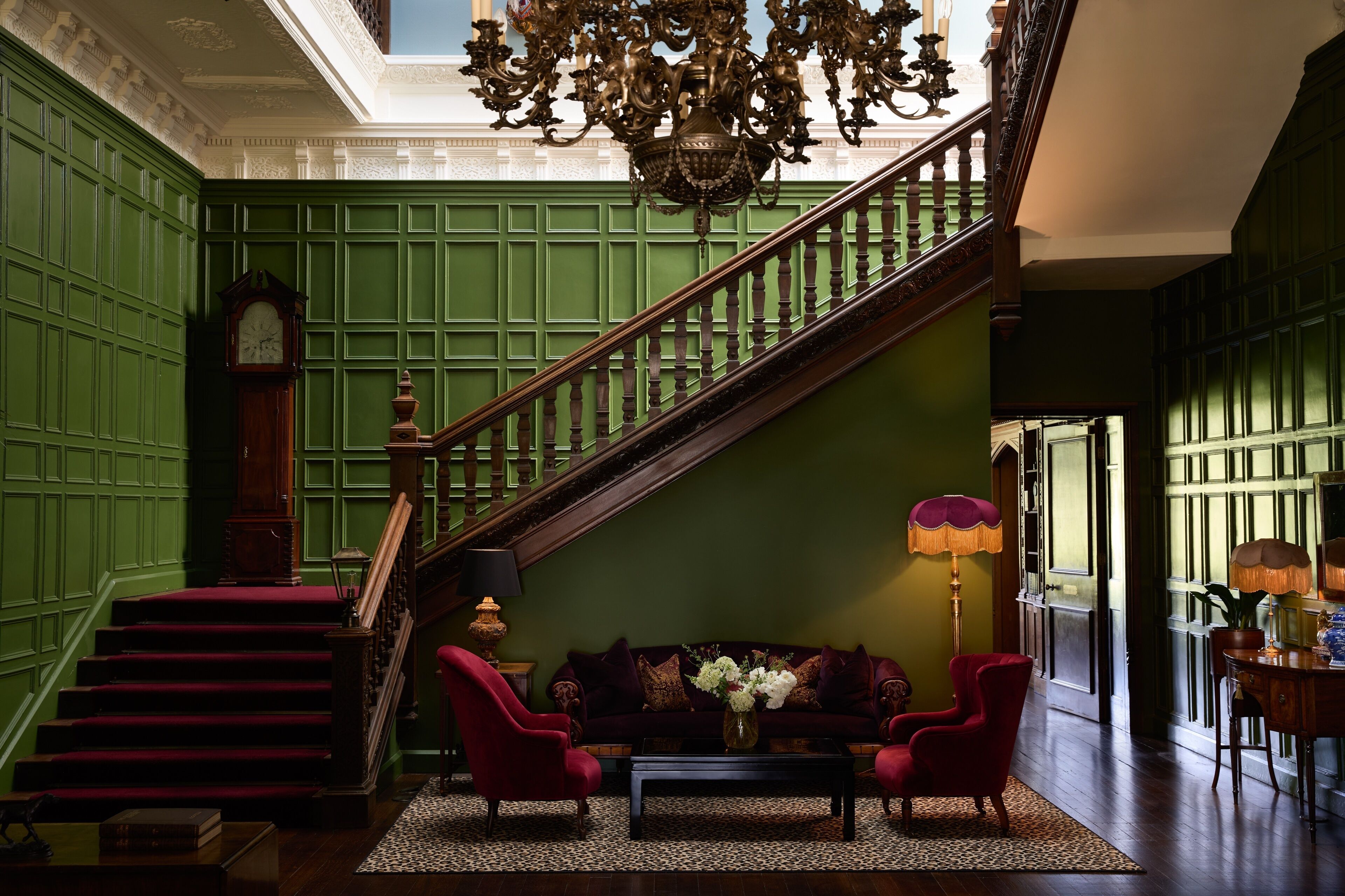 A grand staircase with a wooden handrail and a chandelier.