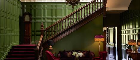 A grand staircase with a wooden handrail and a chandelier.
