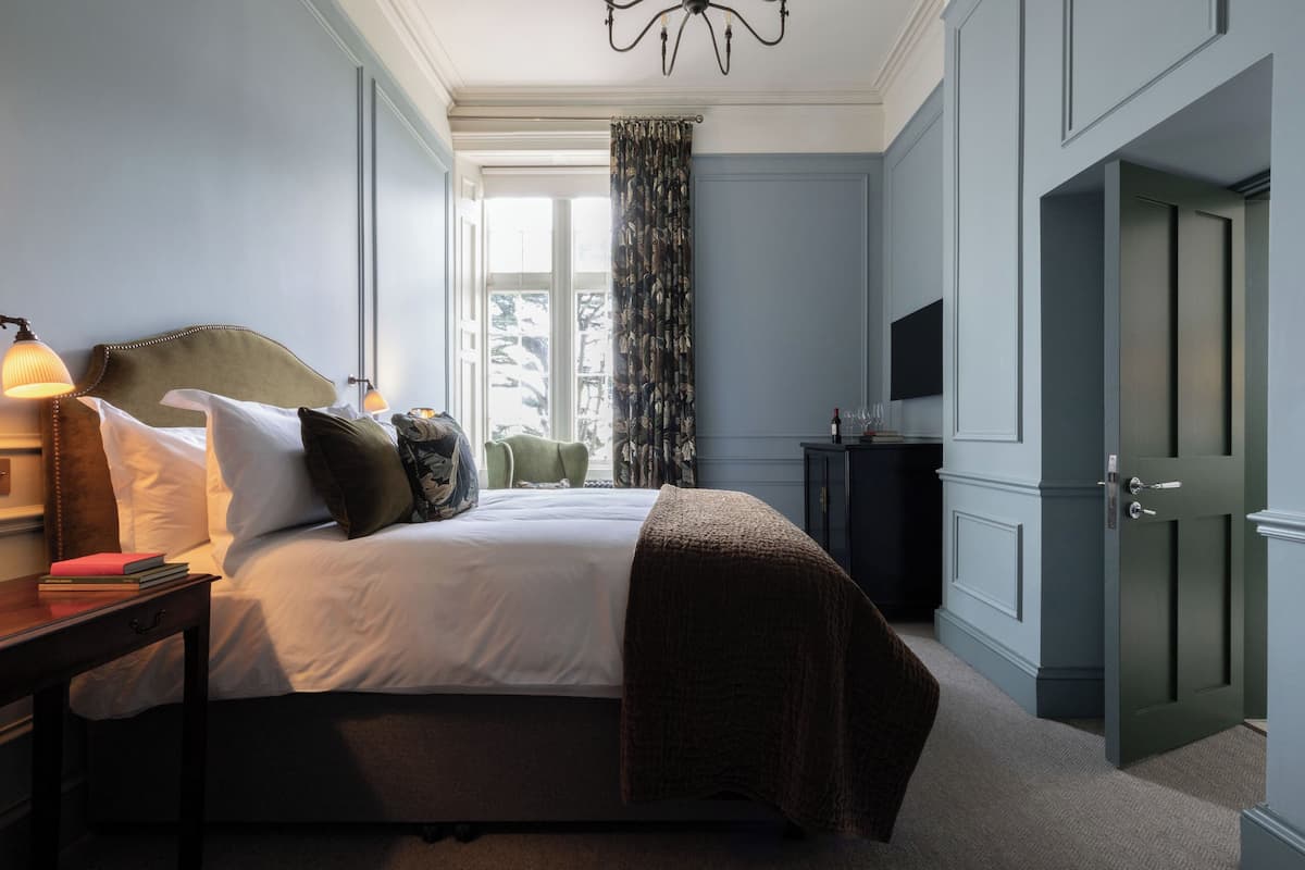 A bedroom with a bed, bedside table, lamp, and a television.
