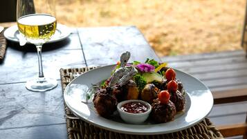 A plate of food with a glass of white wine on a table.