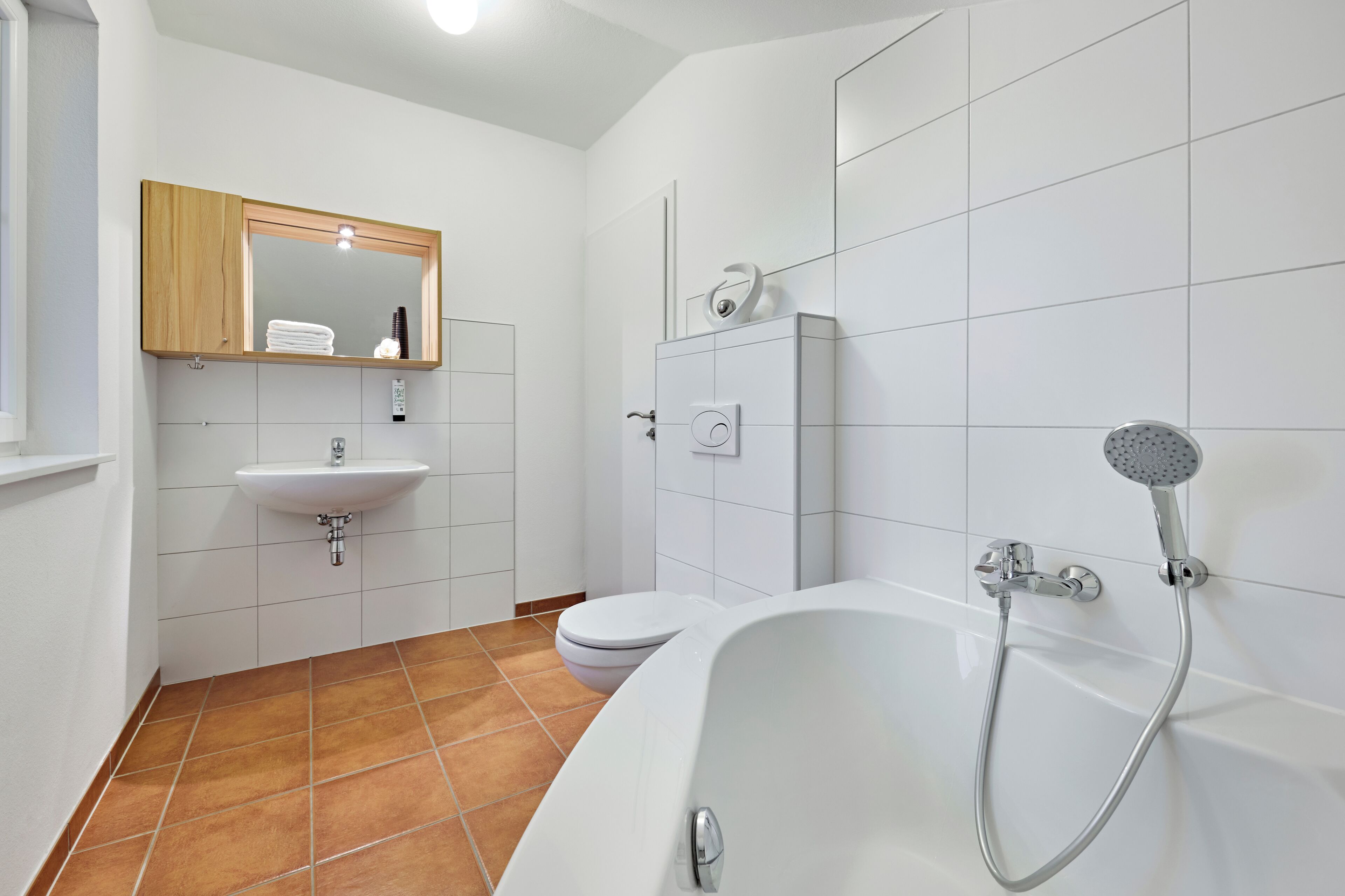 A modern bathroom with a white sink, toilet, and bathtub.