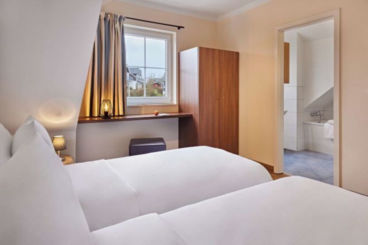 A hotel room with a bed, a desk, a window with curtains, and a view of the outside.
