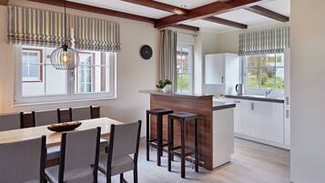 A modern kitchen with a wooden island, bar stools, and a dining area with a table and chairs.