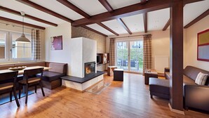Un amplio salón con chimenea, vigas de madera, una mesa de comedor con sillas y un sofá.