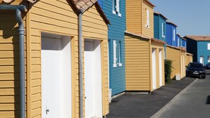 A row of colorful, single-story buildings with a uniform architectural style, likely a residential or vacation rental area. - Résidence Odalys Le Village des Amareyeurs (Le Chateau-d'Oleron)
