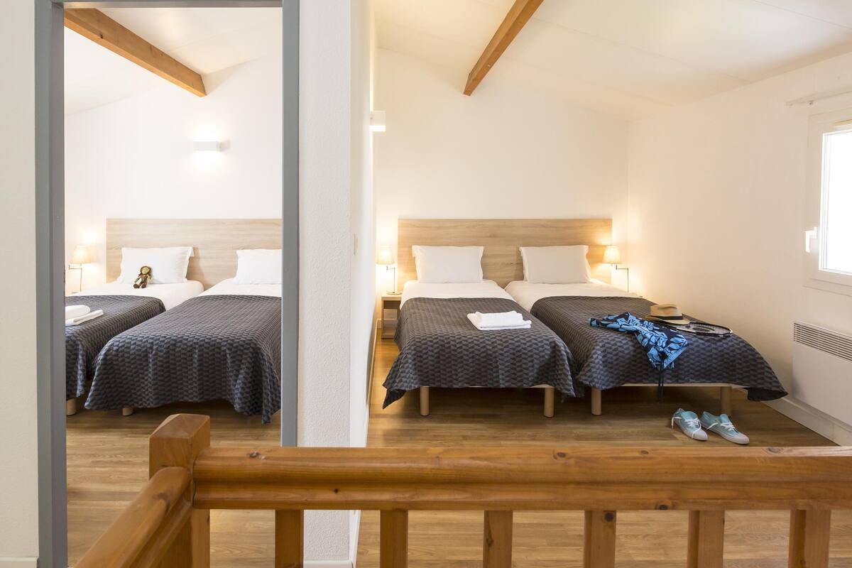 A hotel room with two beds, wooden headboards, bedside lamps, and a window.