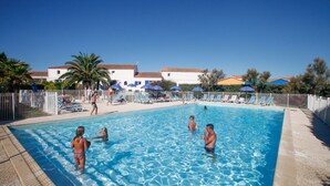 A swimming pool with people in the water, lounge chairs, and umbrellas. - Résidence Odalys Le Village des Amareyeurs (Le Chateau-d'Oleron)