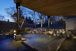A heated outdoor pool area with stone accents and a wooden pergola. - Karuizawa Prince Hotel West (Karuizawa)