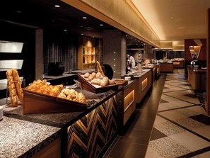 A hotel kitchen with a buffet area featuring bread and pastries. - Karuizawa Prince Hotel West (Karuizawa)