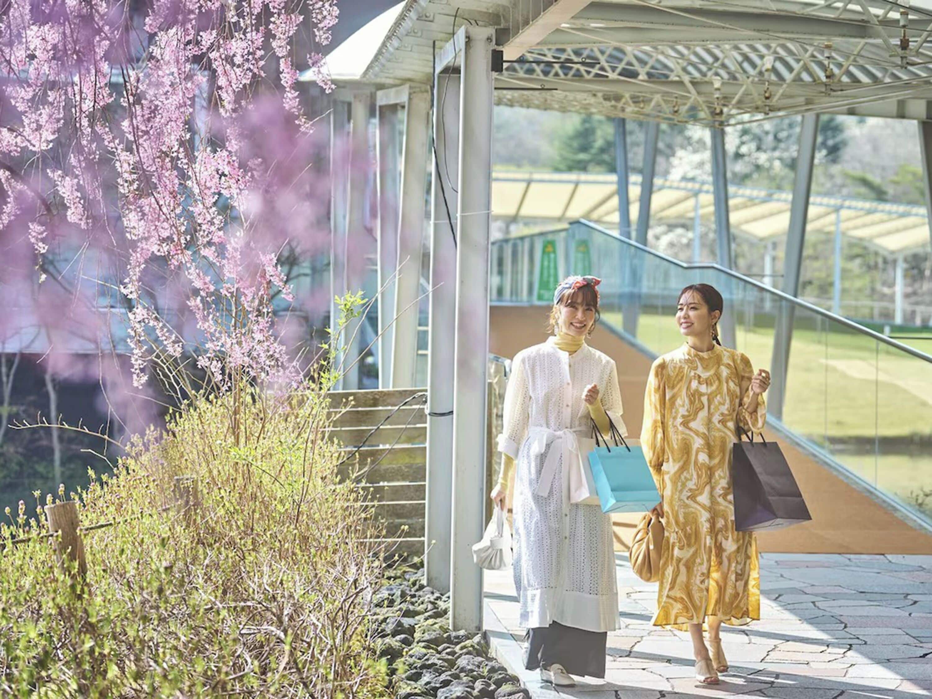 Two people walking outside a building with a covered walkway and a view of a park.