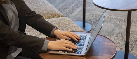 Una persona usando una computadora portátil sobre una mesa redonda de madera en un ambiente interior moderno.