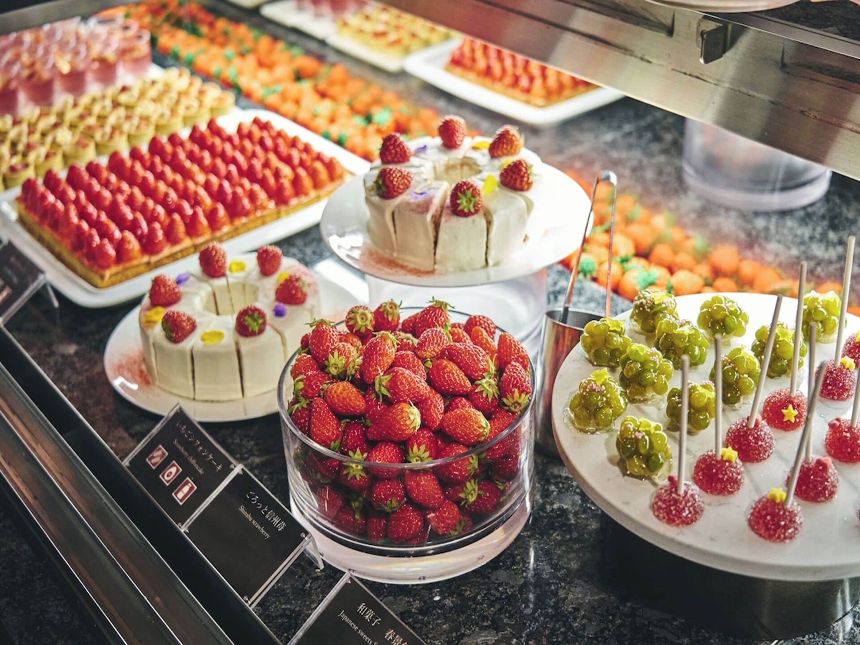 A variety of desserts including cakes and fruit tarts displayed in a buffet setting.