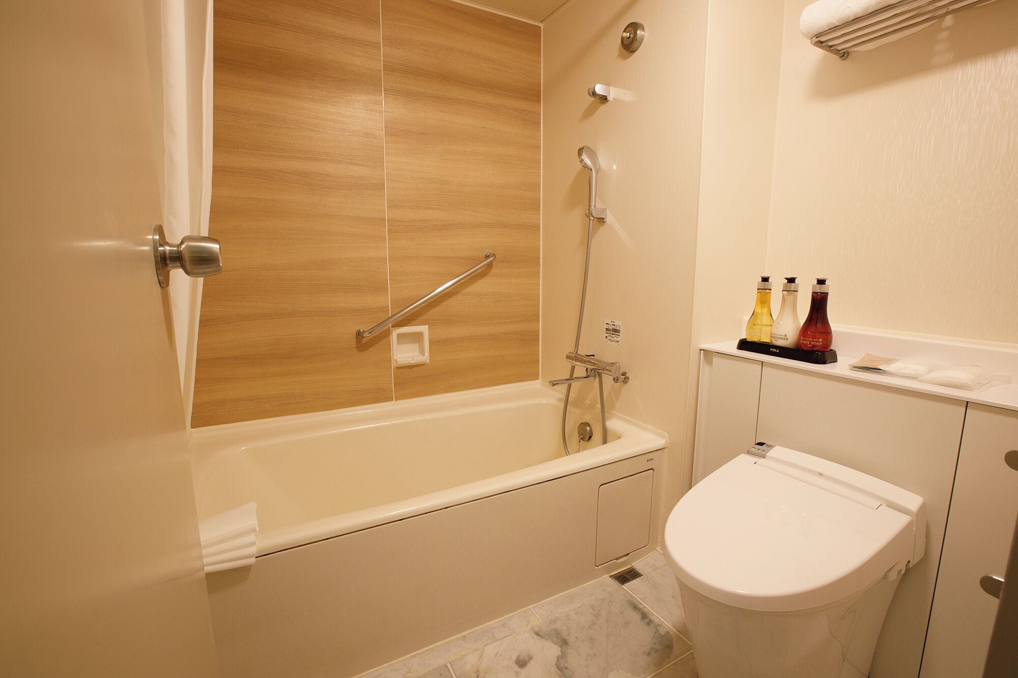 A bathroom with a bathtub, a toilet, and a shelf with toiletries.