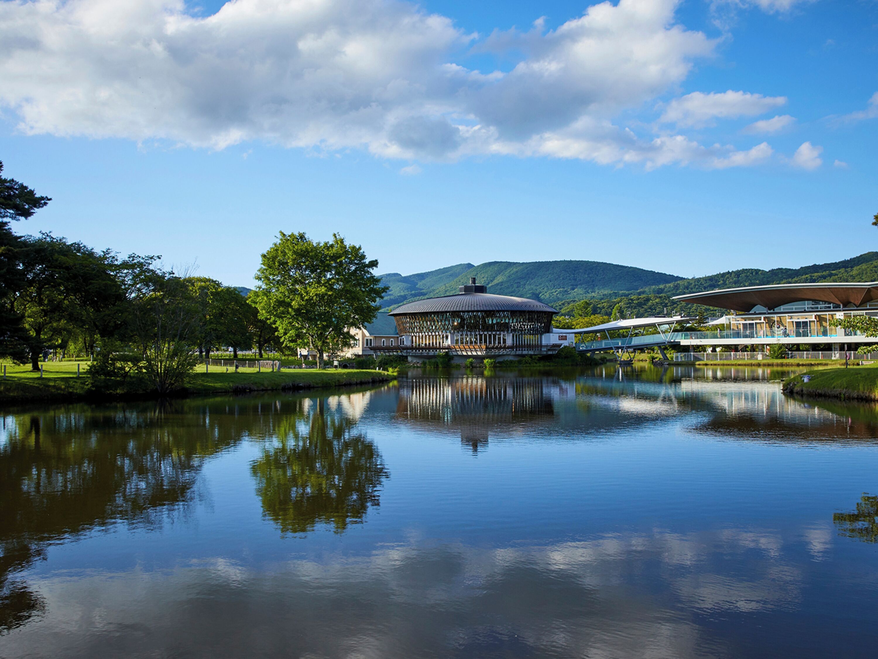 A lakeside view with a pavilion, a building with a dome, and a restaurant with a modern design.