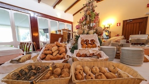 Uma mesa de buffet com diversos produtos de panificação e um centro de mesa decorativo.