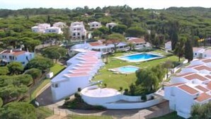 Vista aérea de um resort com vários edifícios, uma piscina e vegetação exuberante.